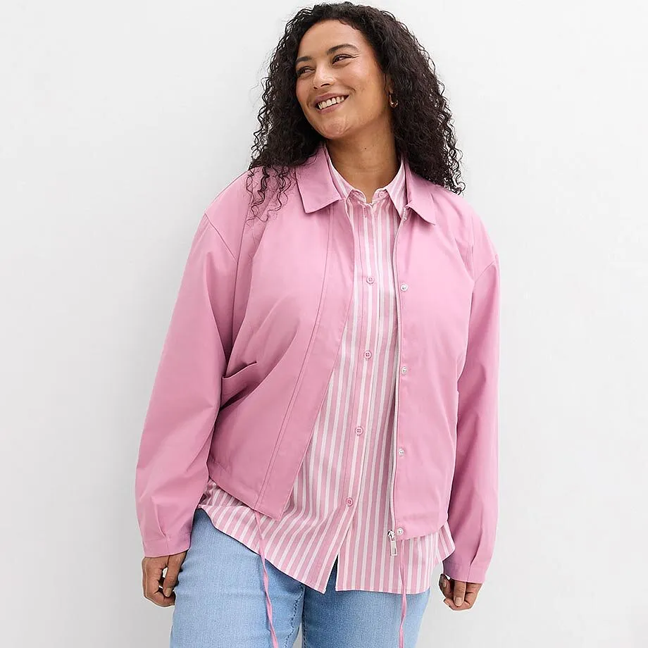 Blouson rose sur une chemise ray&eacute;e, associ&eacute; &agrave; un jean bleu.