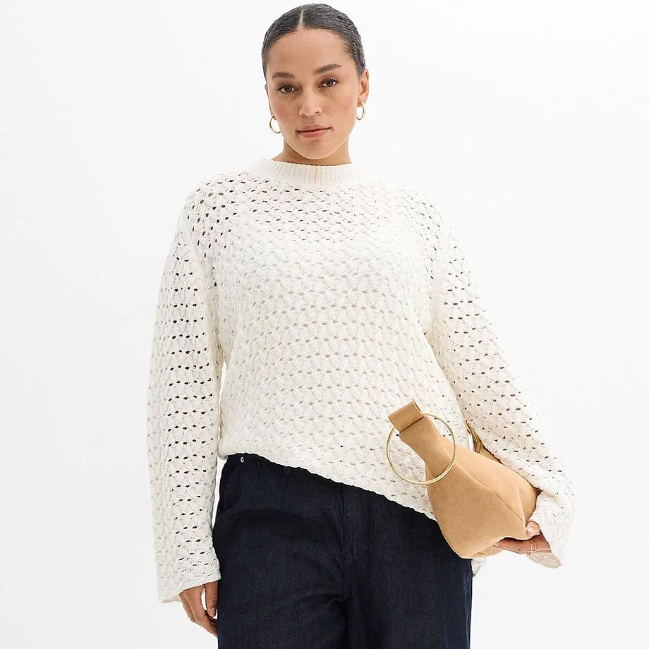 Pull blanc en maille ajour&eacute;e et pantalon bleu fonc&eacute;.