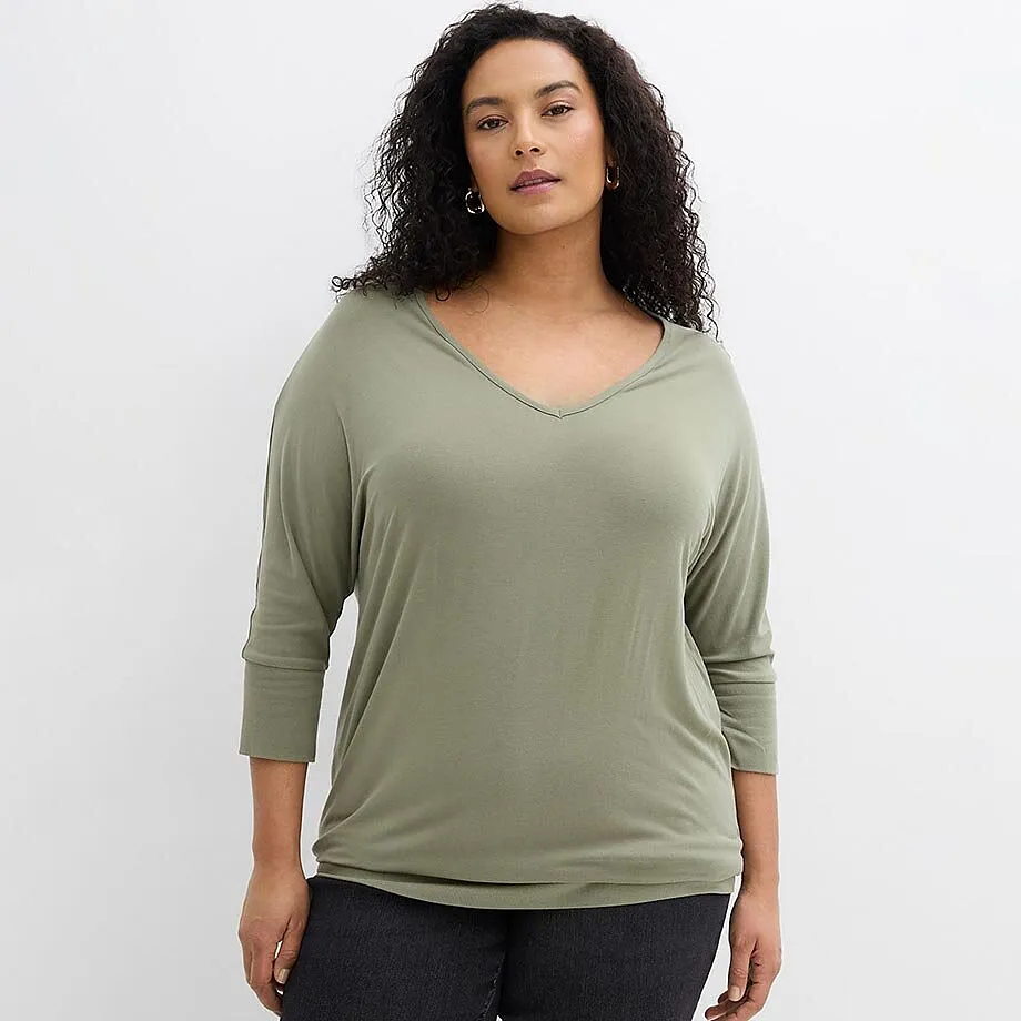 Look d&eacute;contract&eacute; : T-shirt vert sauge avec d&eacute;collet&eacute; en V et jean de couleur fonc&eacute;e.