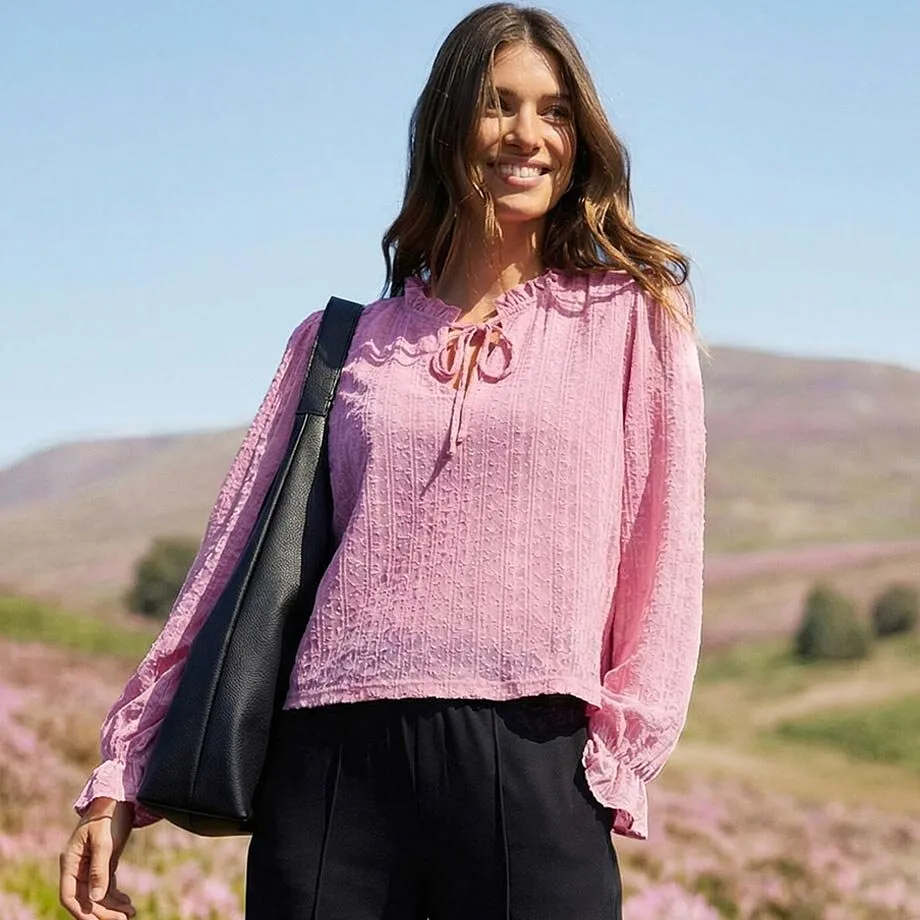 T-shirt rose &agrave; manches longues avec col nou&eacute;, manches fluides et pantalon noir.