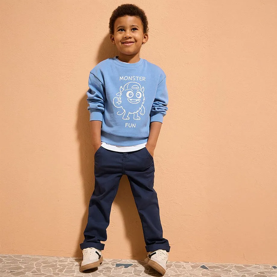 Pull bleu clair &agrave; imprim&eacute; blanc, jean de couleur fonc&eacute;e et chaussures beige pour un style d&eacute;contract&eacute;.