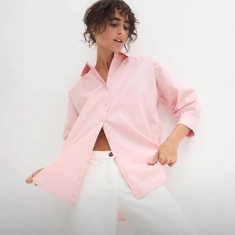 Chemisier rose drag&eacute;e &agrave; manches longues sur un pantalon blanc.