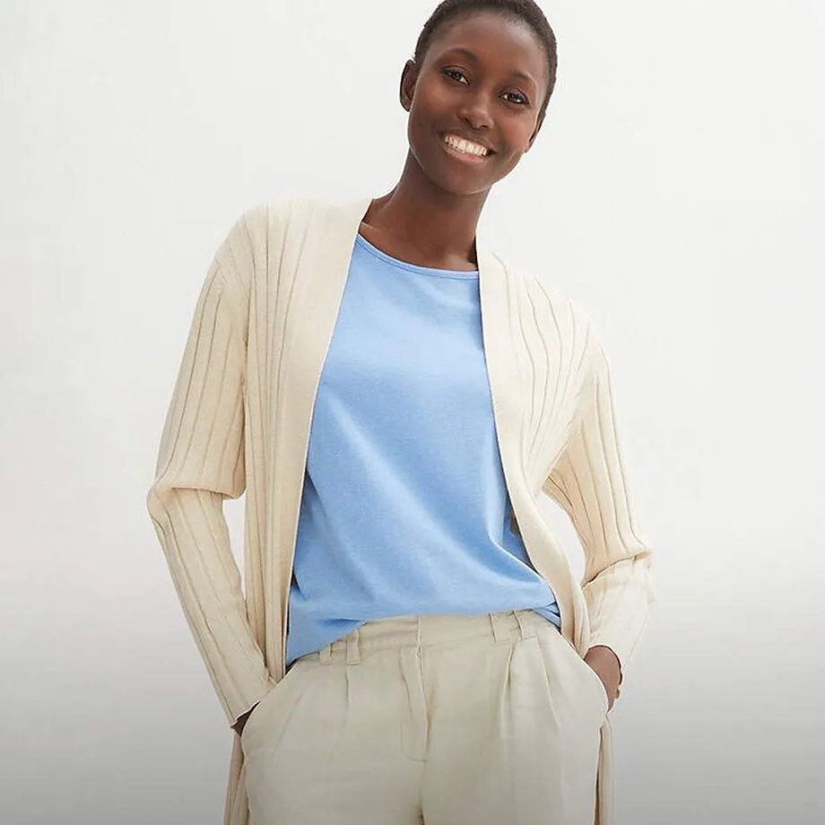 Gilet en maille de couleur cr&egrave;me sur un T-shirt bleu clair, associ&eacute; &agrave; un pantalon de tailleur clair.