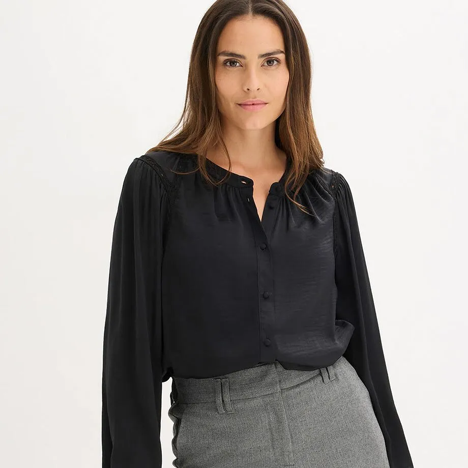 Chemisier noir &eacute;l&eacute;gant avec d&eacute;collet&eacute; en V, associ&eacute; &agrave; un pantalon gris.