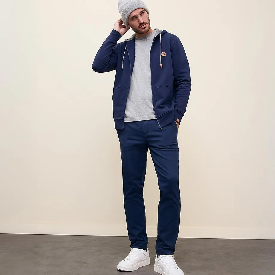 Look d&eacute;contract&eacute; avec gilet bleu marine &agrave; capuche, T-shirt gris et pantalon assorti.