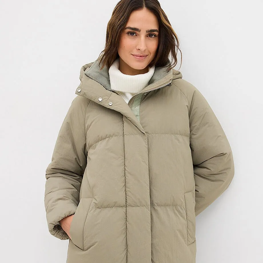 Manteau matelass&eacute; olive fum&eacute; avec col montant et pull blanc en dessous.