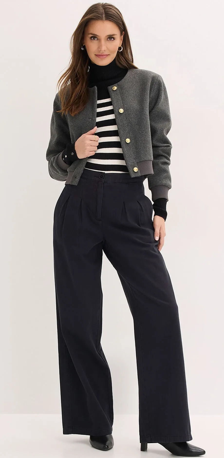 Veste grise, pull ray&eacute; et pantalon large noir.