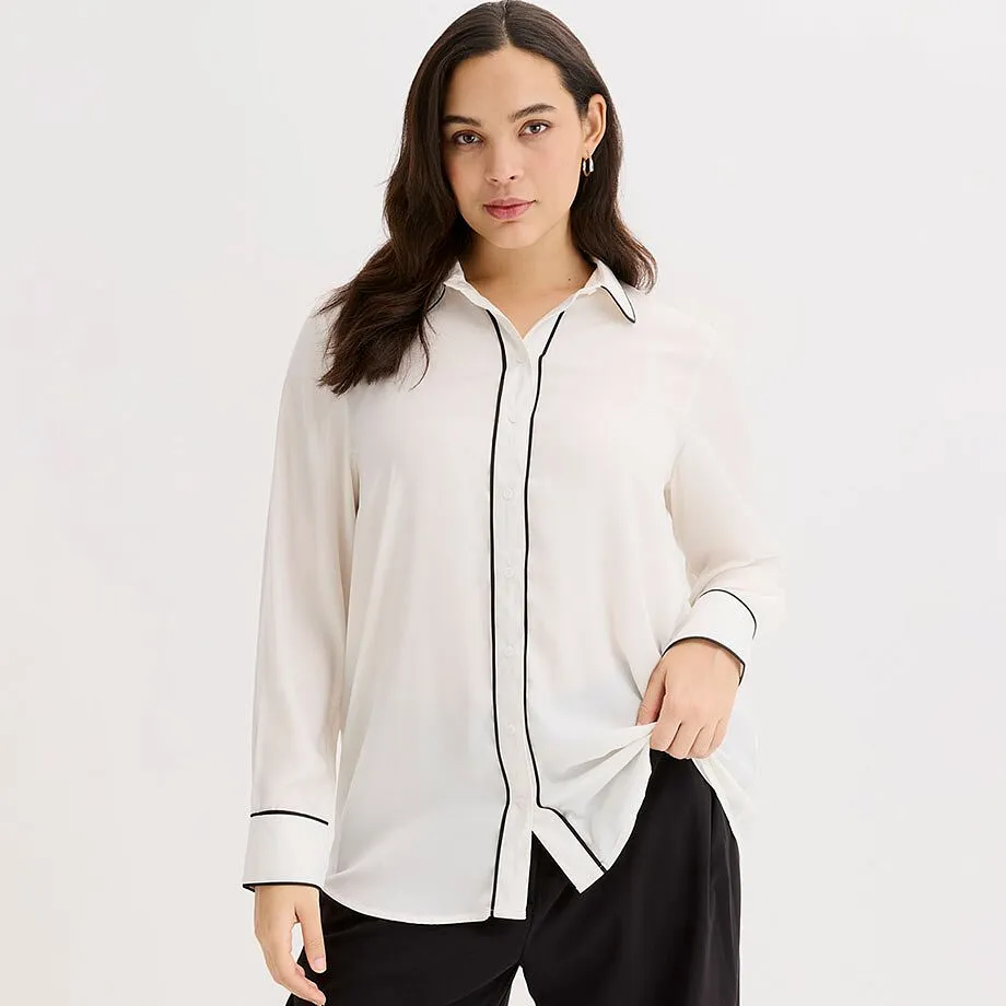 Chemisier blanc avec passepoil noir, col chemise classique et manches longues.