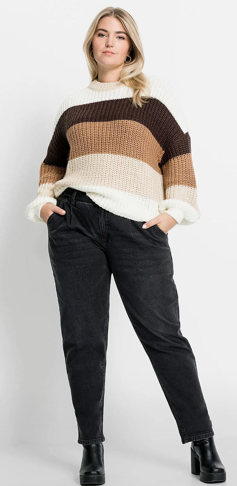 Pull en maille &agrave; rayures dans des tons terreux, port&eacute; avec un jean fonc&eacute; et des chaussures noires.