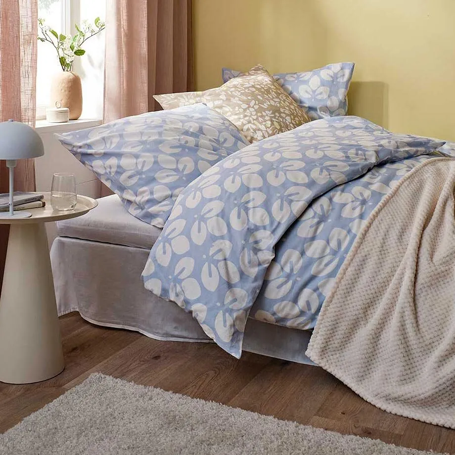 Linge de lit en bleu et blanc, couverture beige et rideaux rose.