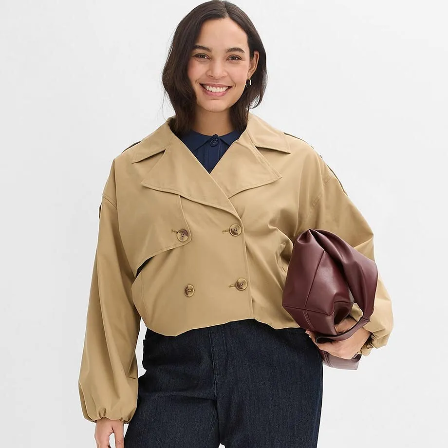 Veste trench beige port&eacute;e par dessus un haut fonc&eacute;. La tenue est compl&eacute;t&eacute;e d'un sac &agrave; main.