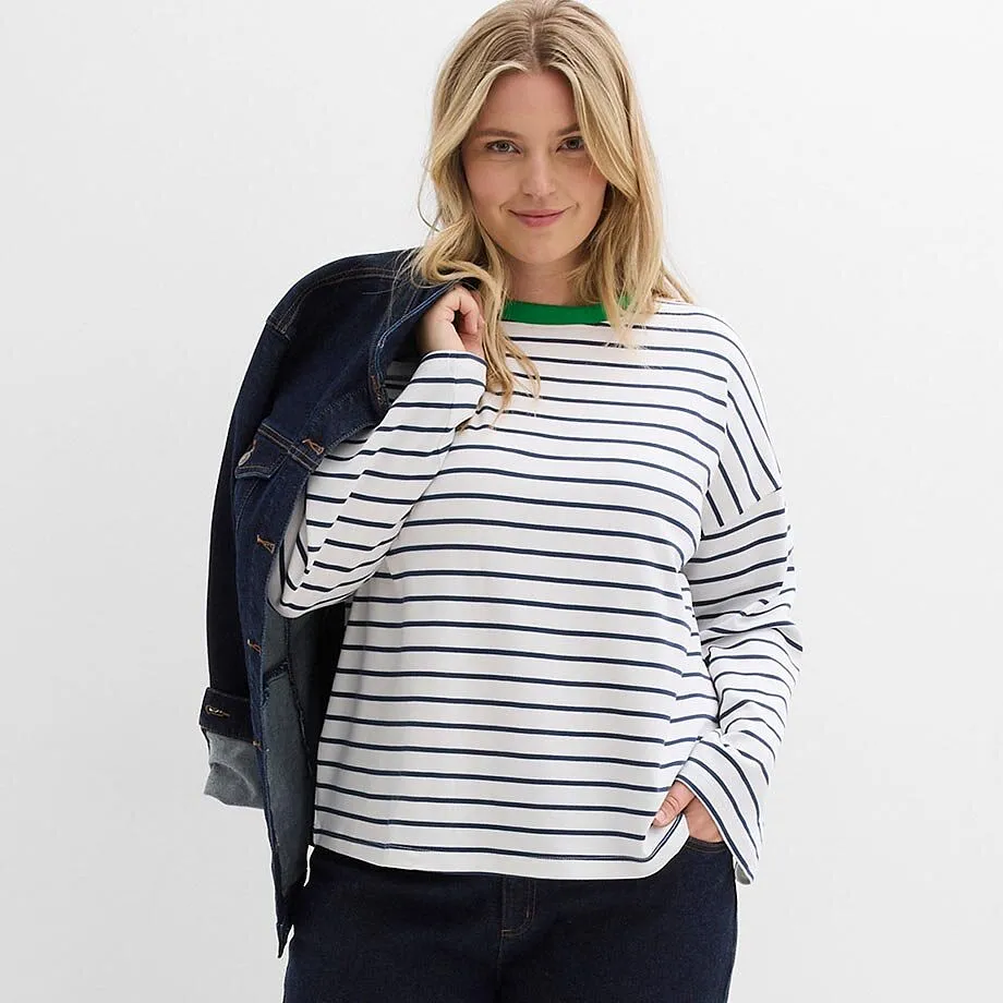 T-shirt ray&eacute; avec col vert, veste en jean bleu fonc&eacute; port&eacute;e par dessus l'&eacute;paule.