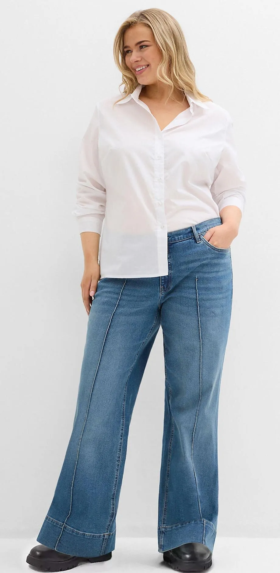 Chemisier blanc associ&eacute; &agrave; un jean de coupe large et des chaussures noires.