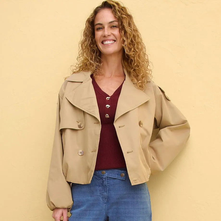 Veste courte beige par dessus un haut rouge bordeaux, associ&eacute; &agrave; un jean classique.