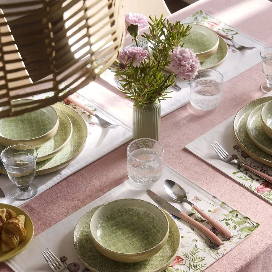 Table avec nappe rose, sets de table printaniers et assiettes vert clair.