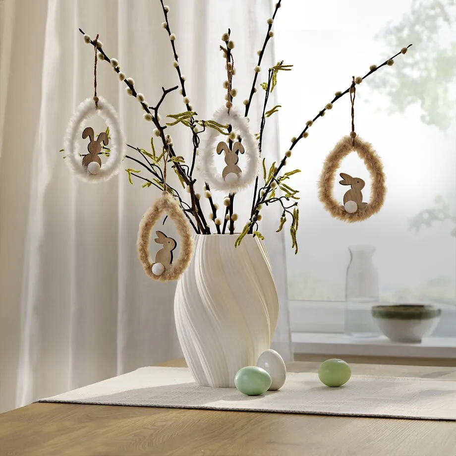 Branches avec d&eacute;corations de P&acirc;ques dans un vase blanc.