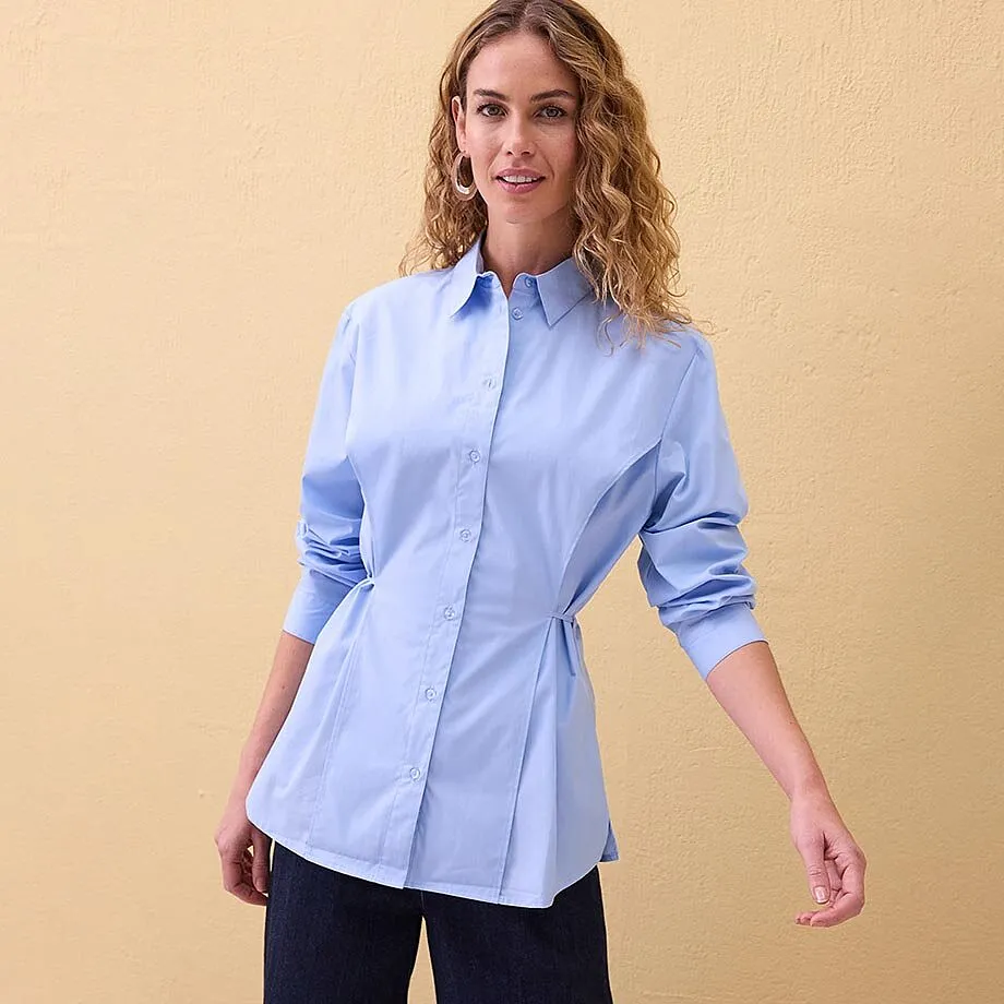 Chemisier bleu clair avec boutons et col, associ&eacute; &agrave; un pantalon fonc&eacute;.