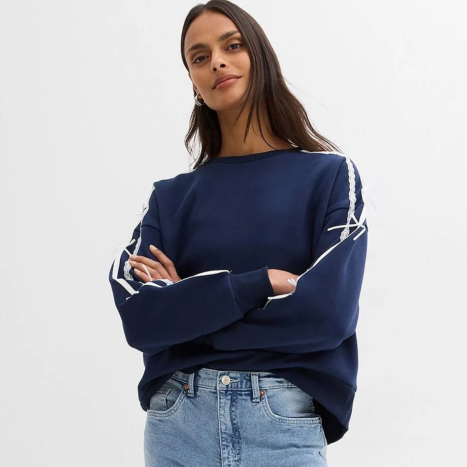 Sweat-shirt bleu avec rayures blanches sur les manches et un jean classique.